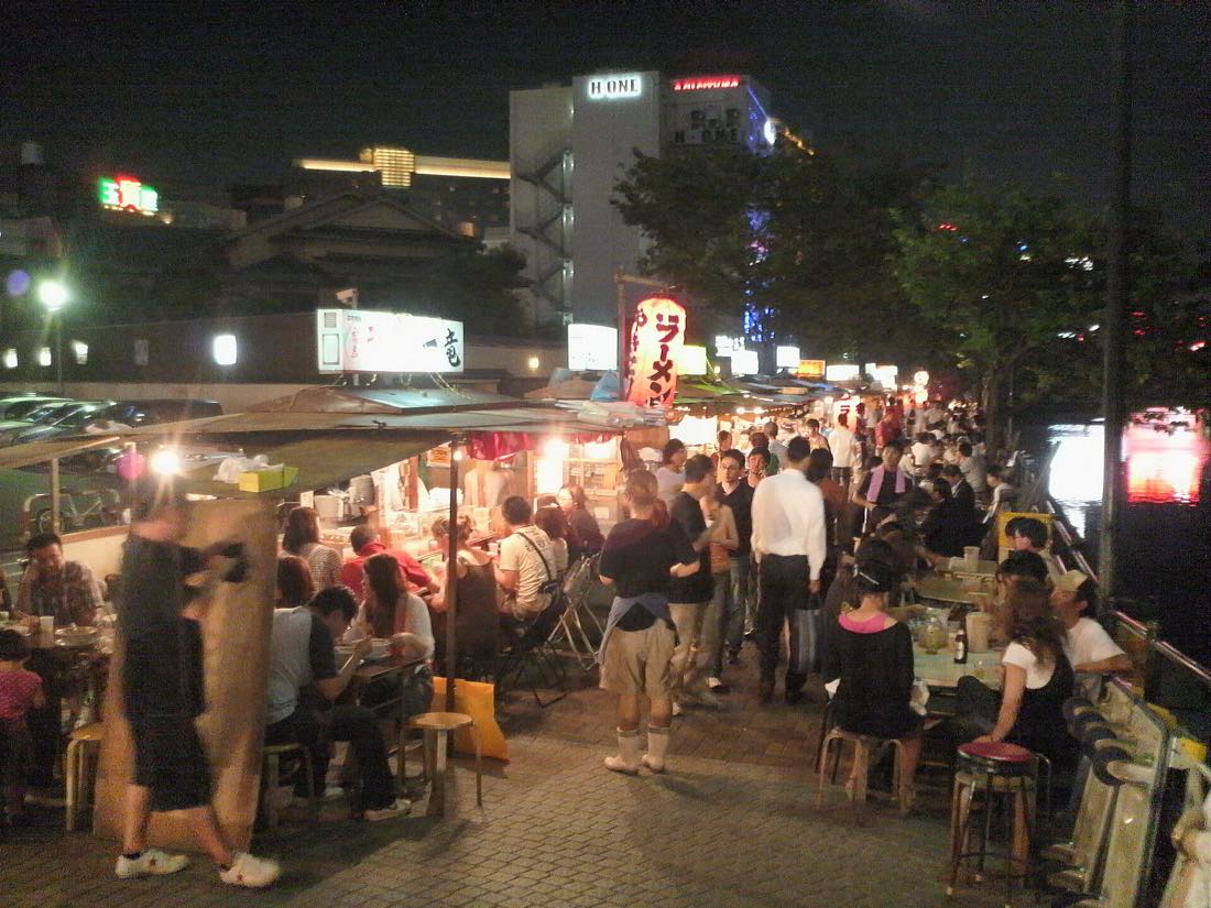 Customers packed onto the stools of a yatai stall at night in Fukuoka